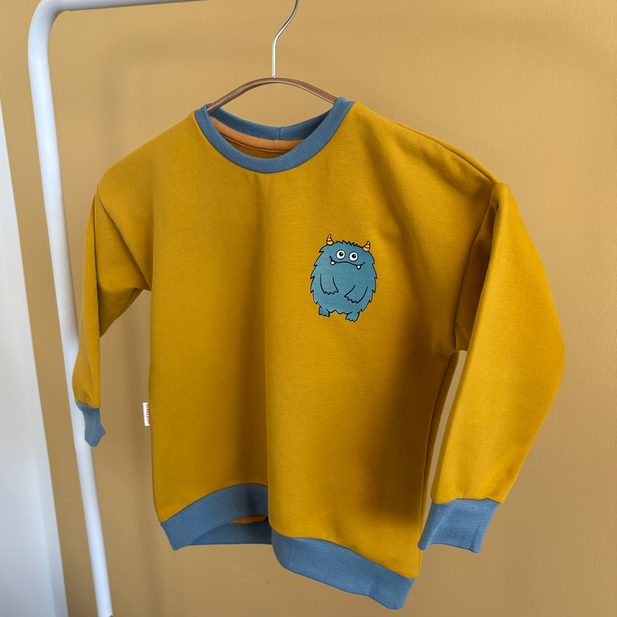 Kuscheliger Monster-Sweatpullover in Senf mit petrolfarbenem Metallic-Patch
