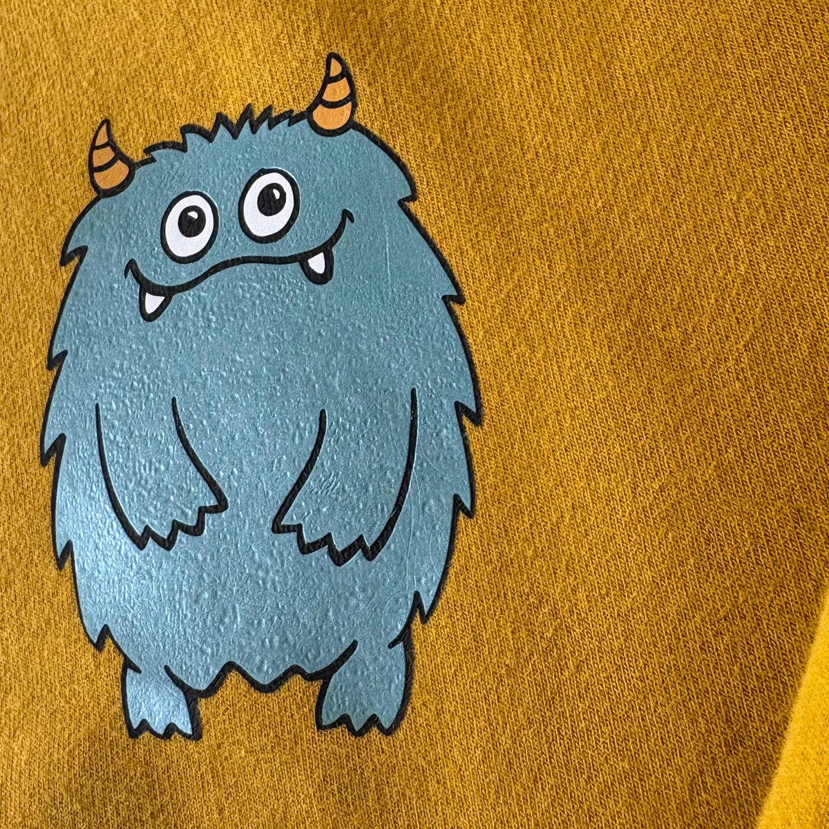 Kuscheliger Monster-Sweatpullover in Senf mit petrolfarbenem Metallic-Patch